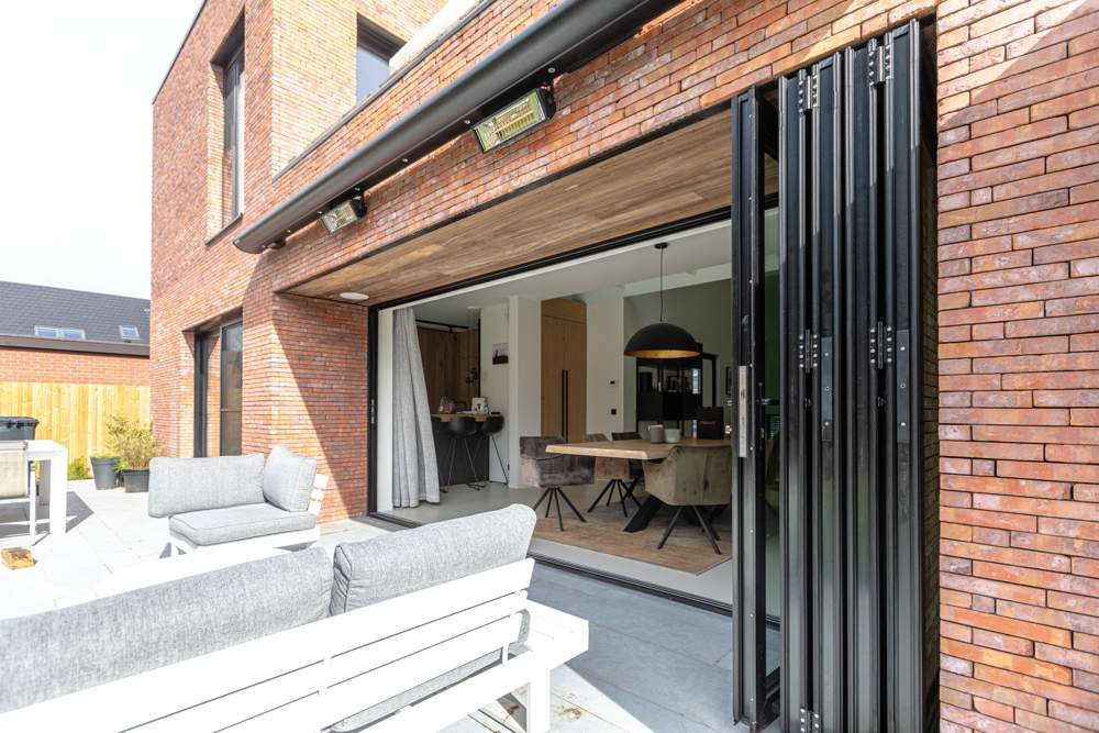 Black bi-fold doors folded open on a brick extension