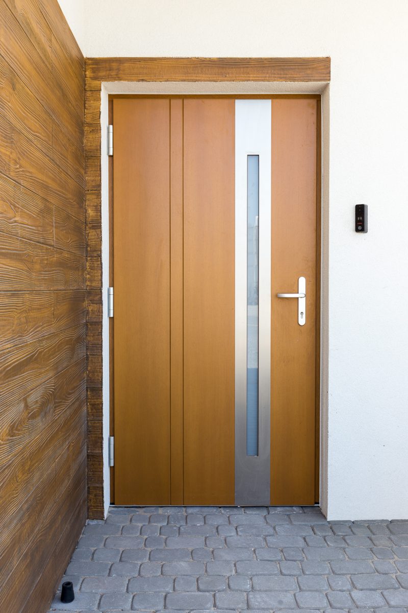 Timber-effect front door with a stainless steel and glass strip beside a timber-clad wall