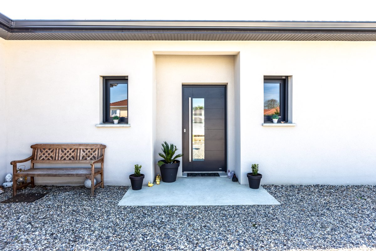 Dark front door with a narrow glass strip in a white single-storey house