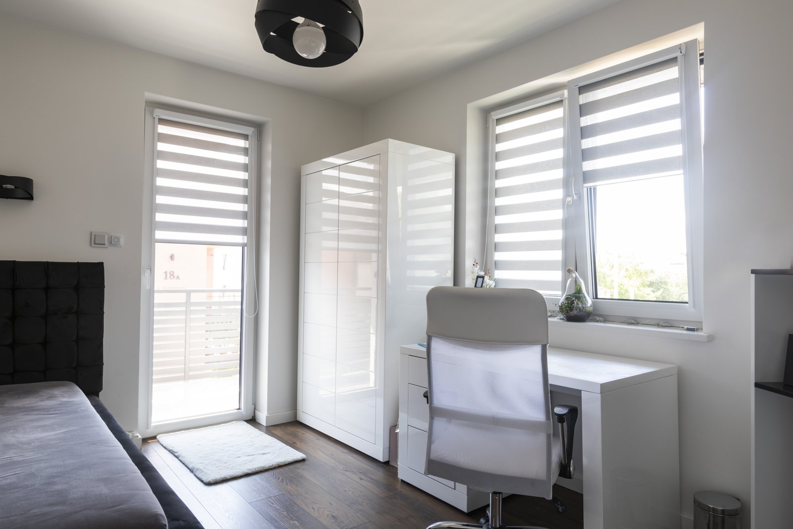 Striped day and night blinds on white windows in a bedroom