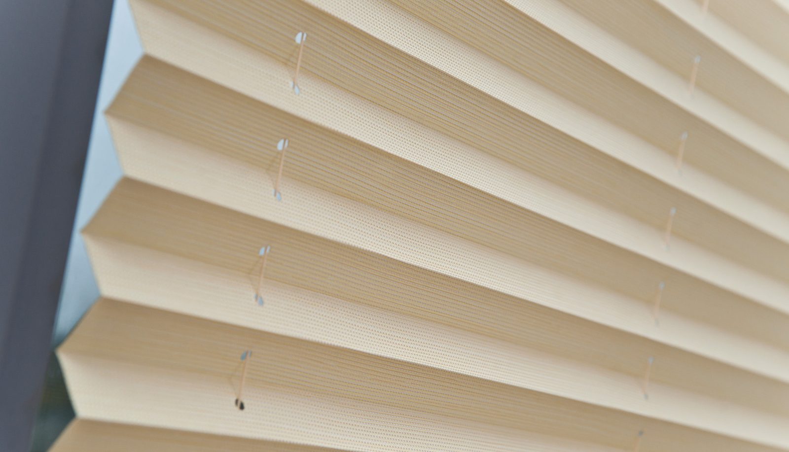Close view of a pleated blind in a cream fabric