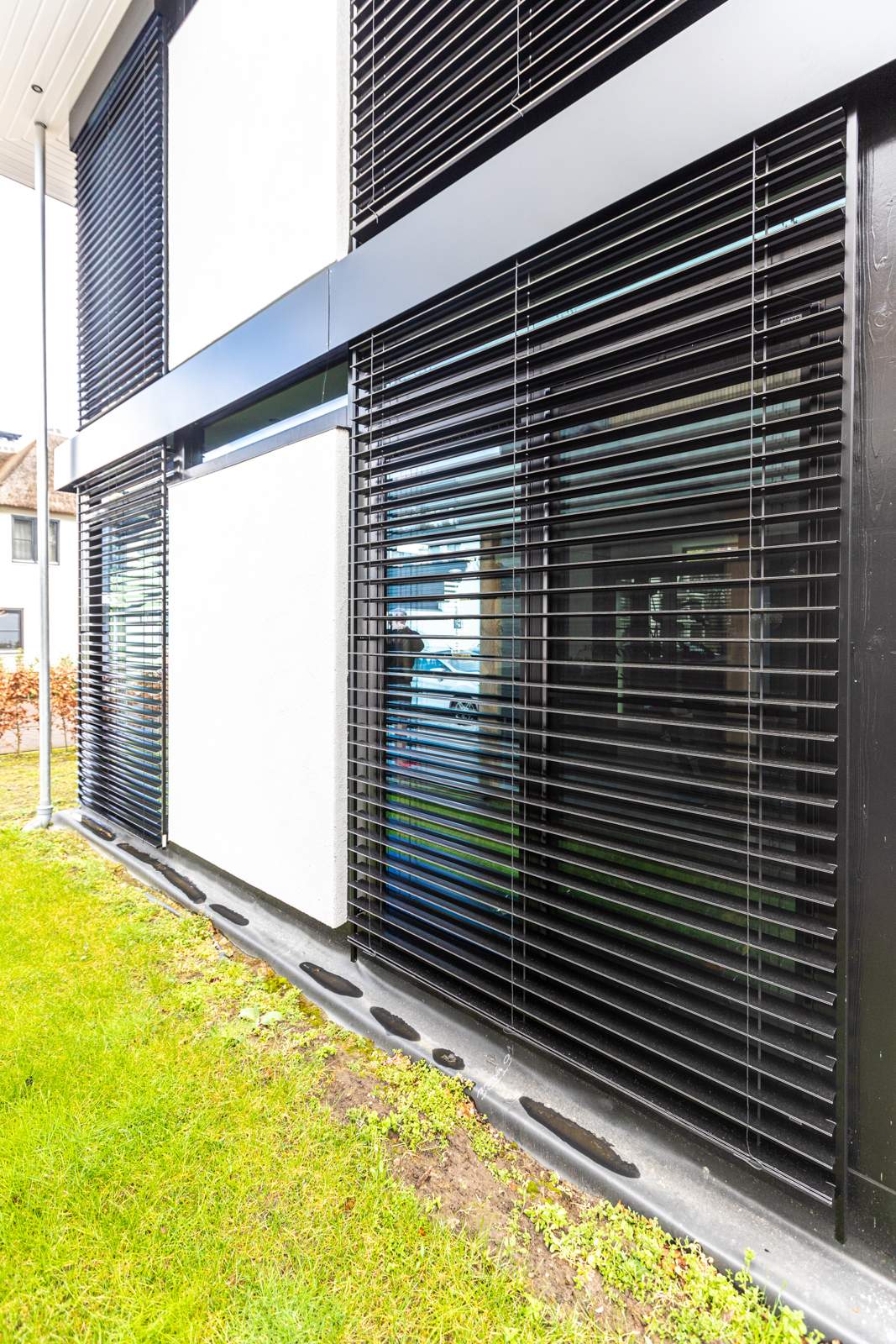 Black external slatted blinds over a corner glazing