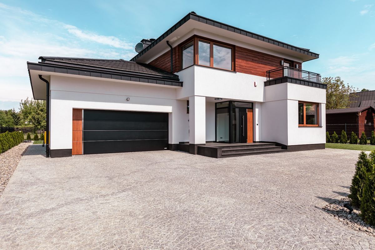 Two-storey house with an anthracite double garage door and timber accents